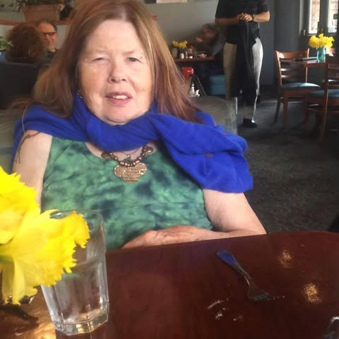 Hunter Reeve at a café table with daffodils, wearing a blue scarf
